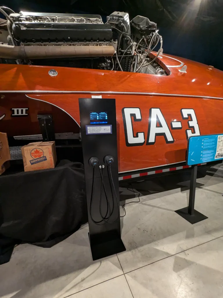 An audio Station in front of a large boat in a museum.