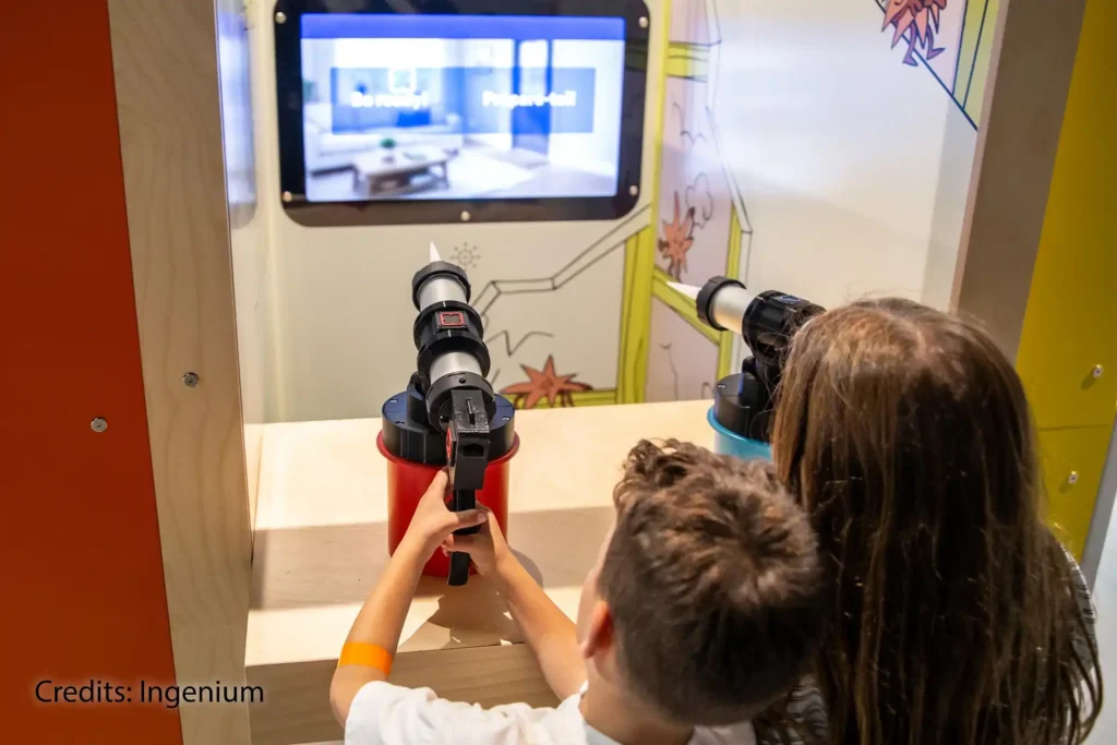 Kids using caulking guns at the "Shoot the leaks" interactive station at Inside the Walls Exhibition